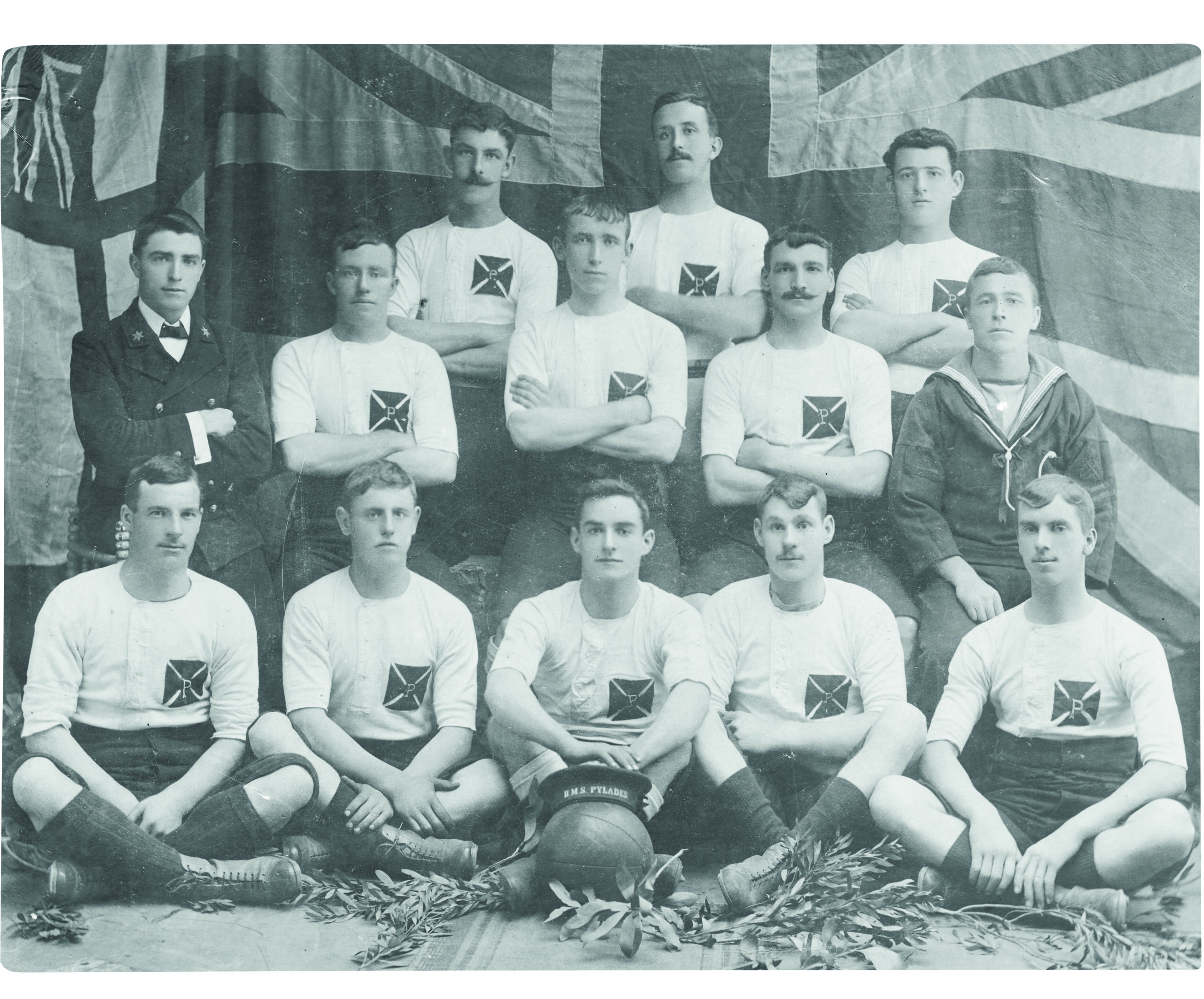 Black and white photograph of the crew of a First World War Navy ship posing in front of a Union Jack