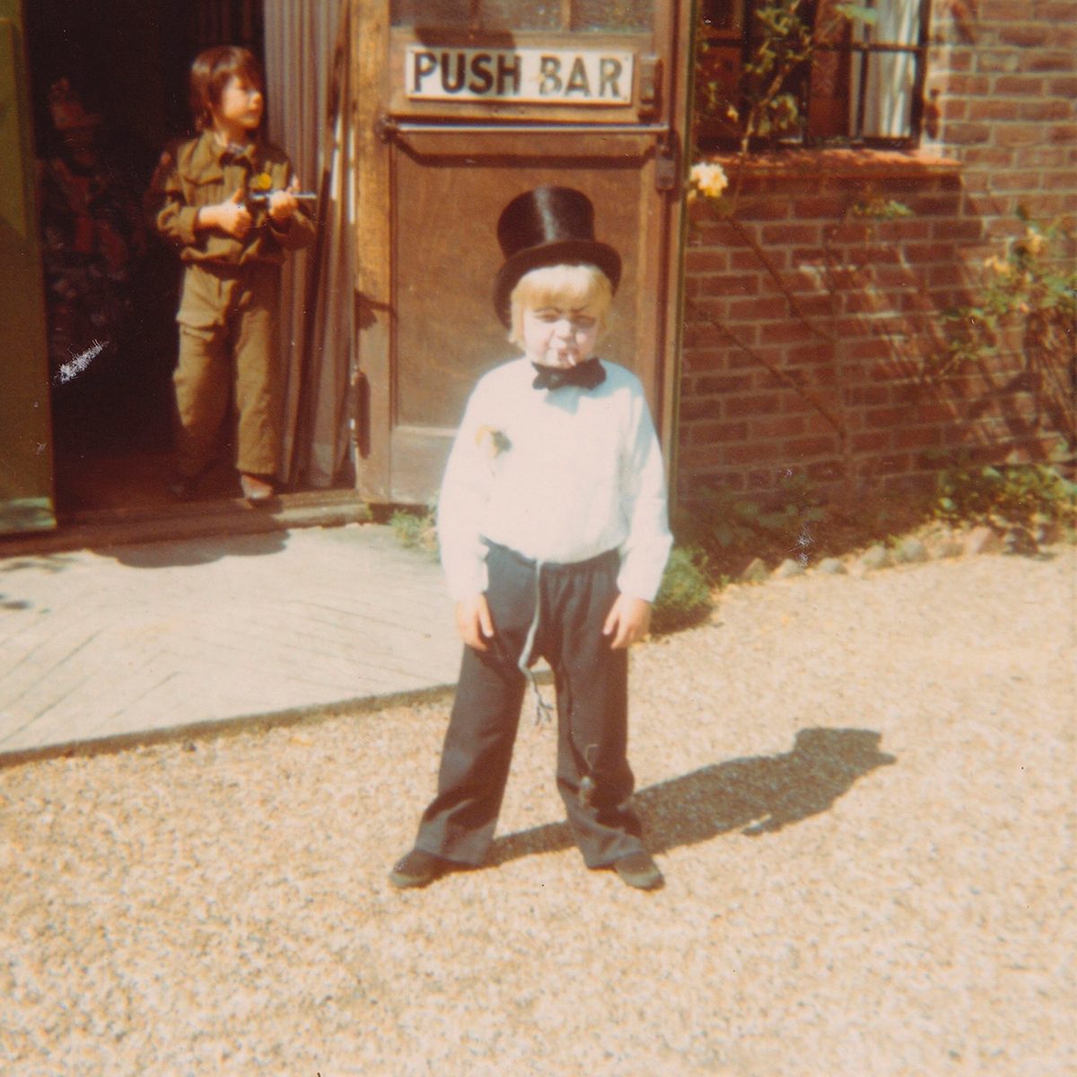 Toby Jones as a child wearing a top hat and white shirt