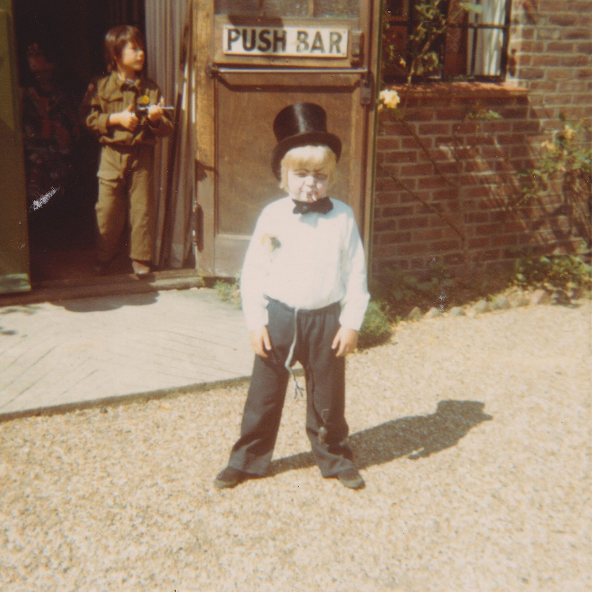Toby Jones as a child wearing a top hat and white shirt