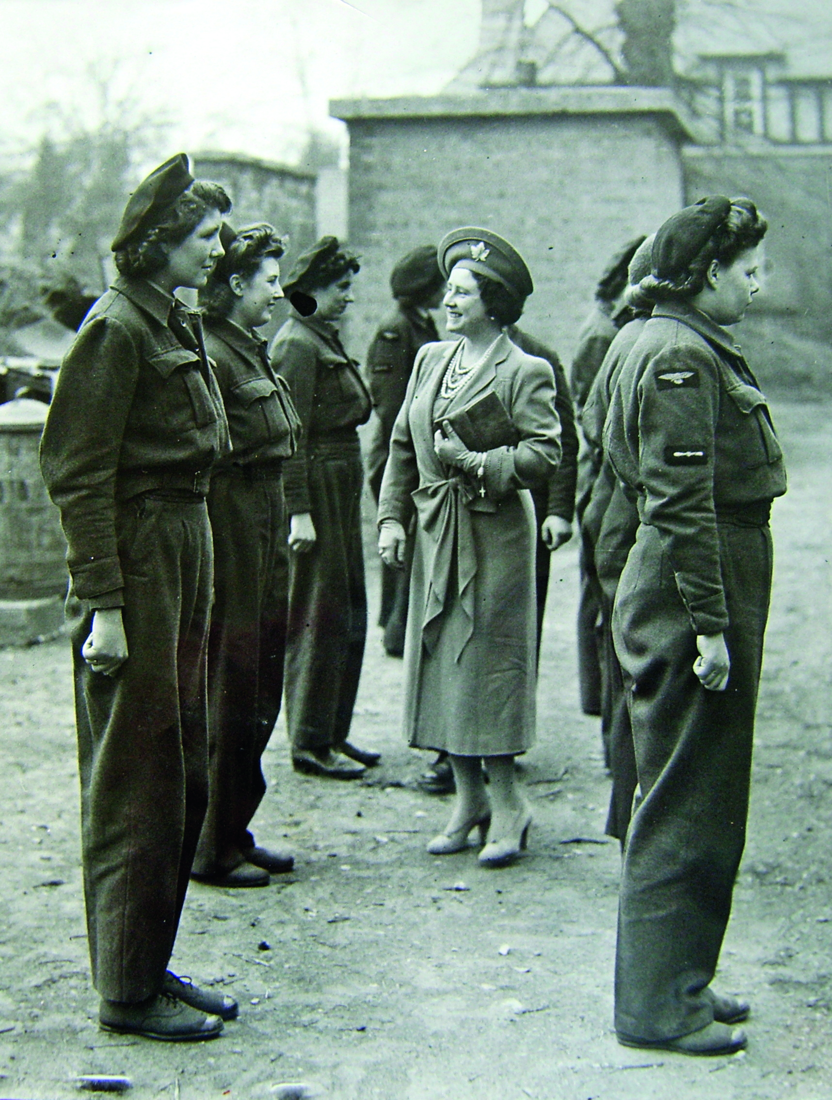 Black and white photograph of Queen Elizabeth inspecting a row of women in airforce jumpsuits during the Second World War