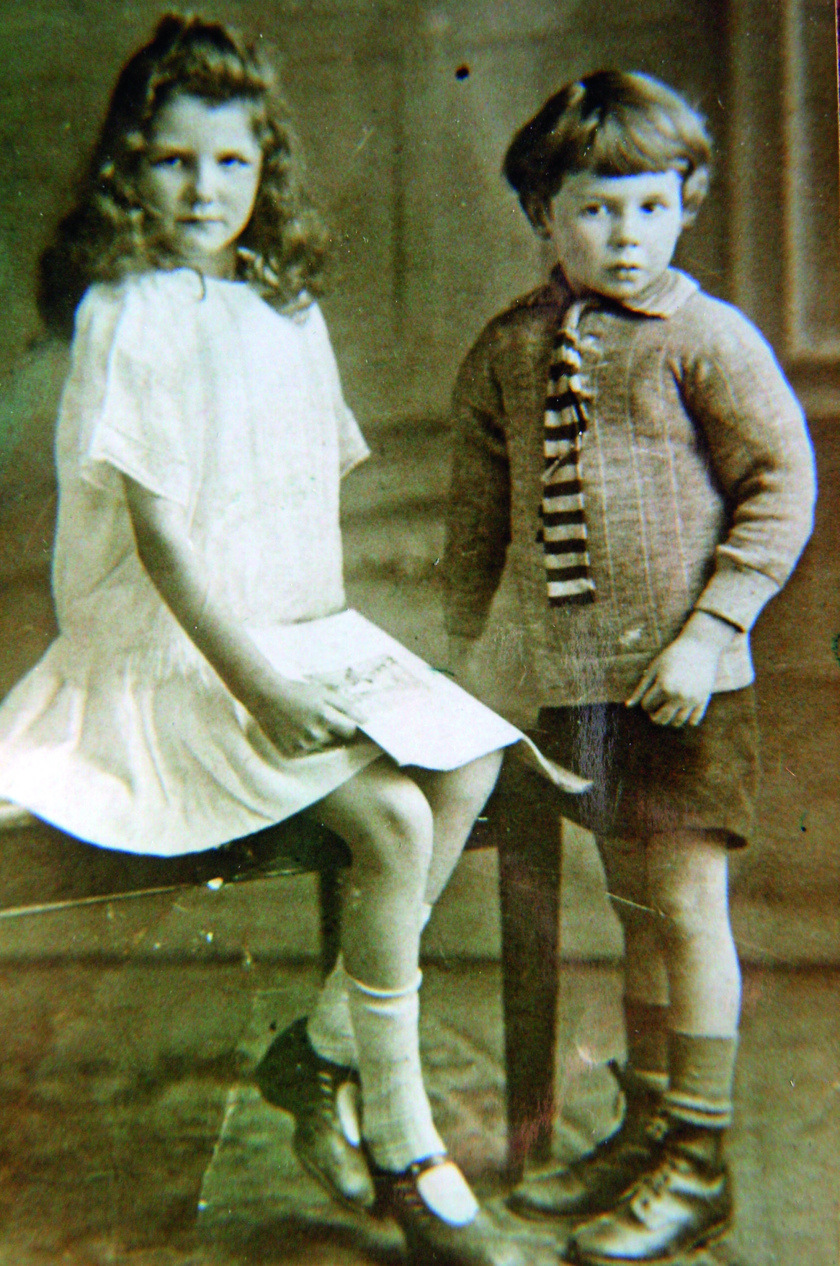 A black and white photograph of a young boy and girl in old-fashioned clothes