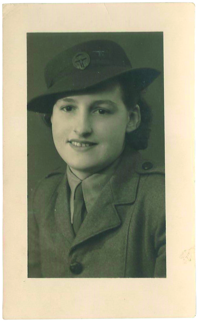 Black and white portrait photograph of a young woman wearing a hat with a military crest on it