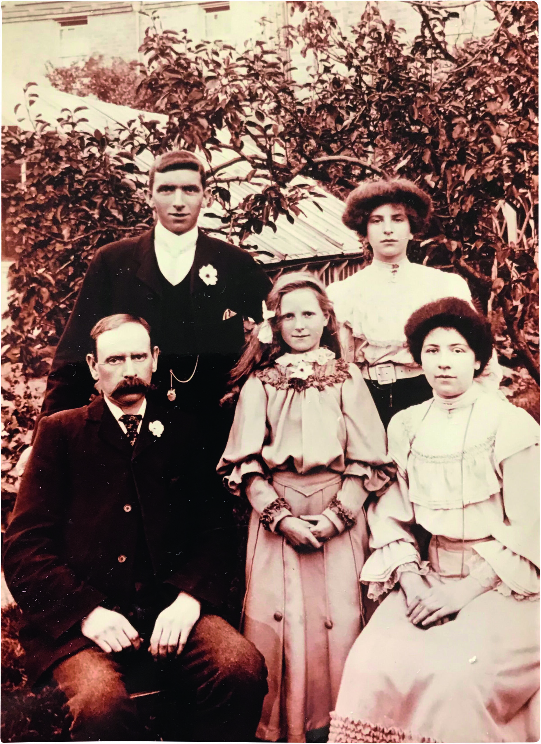 Black and white photograph of a little girl, a middle-aged man, two young women and a young man in Edwardian dress