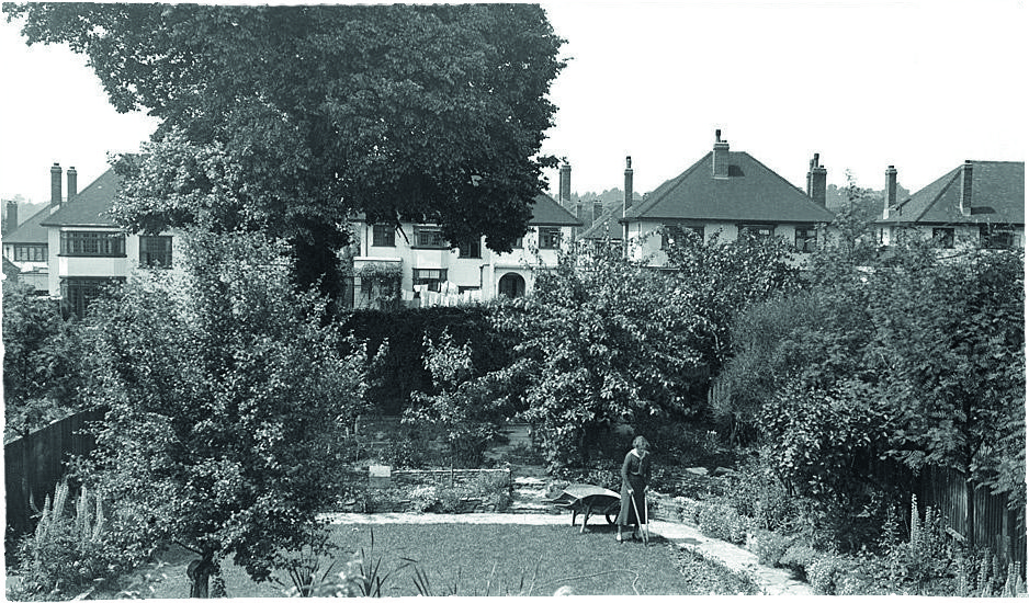 Black and white photograph of a woman in a suburban back garden