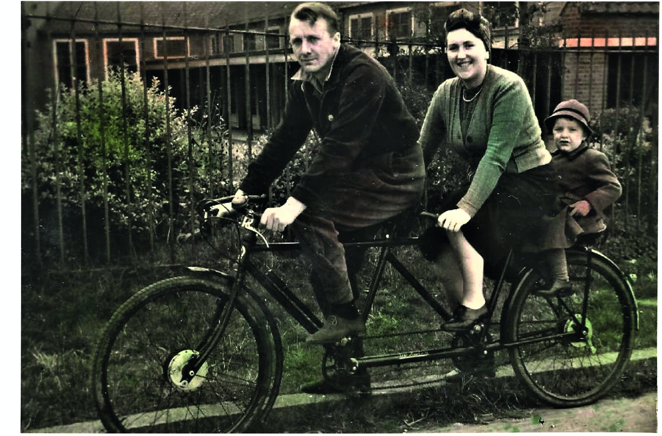 Black and white photograph of a man, a woman and a little boy riding a tandem