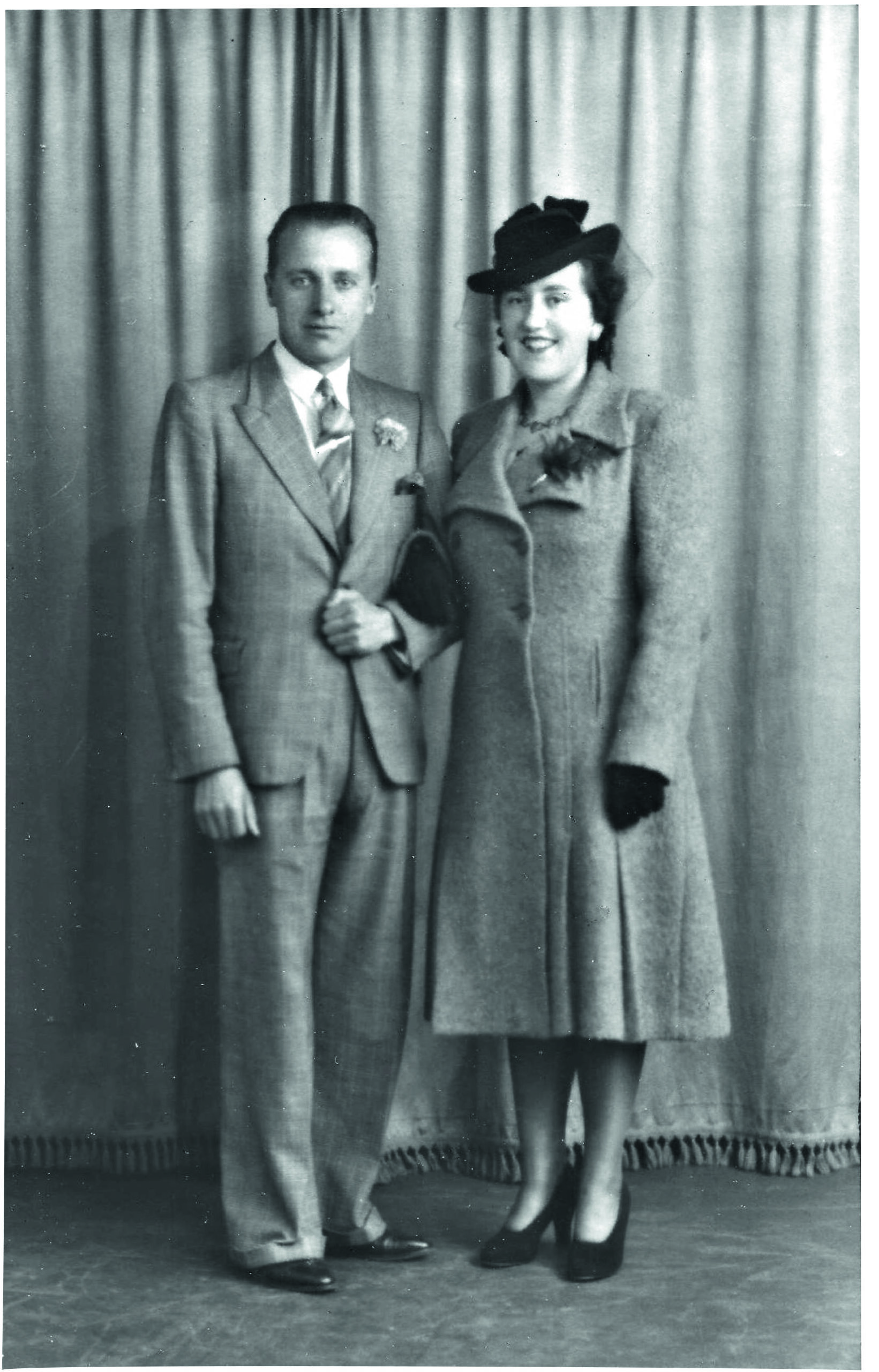 Black and white photograph of a man wearing a suit and a woman wearing a hat with a veil posing for their wedding