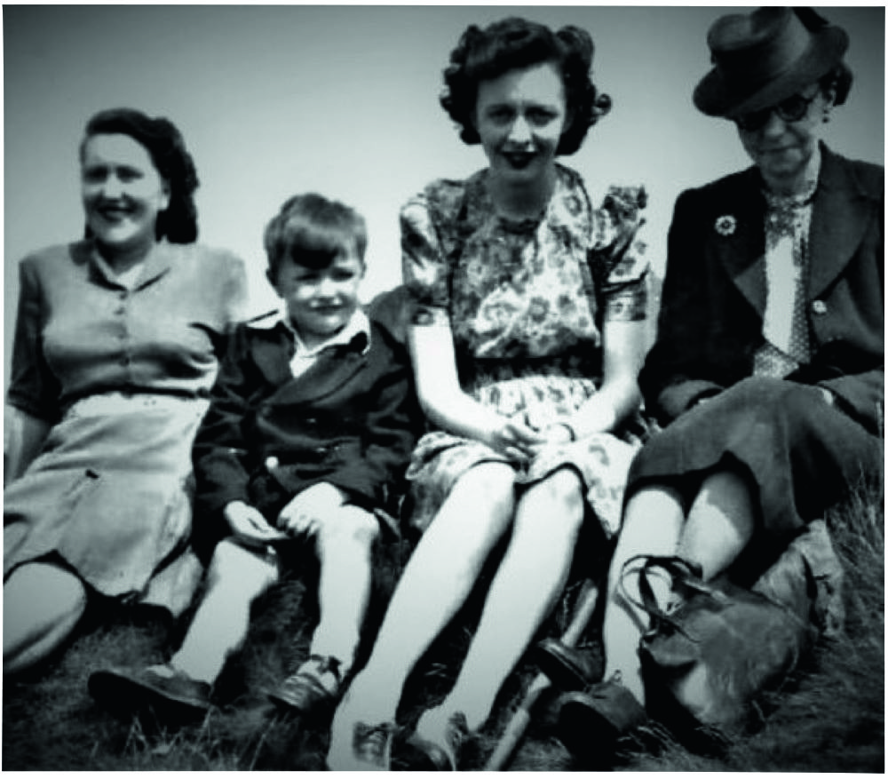Black and white photograph showing two younger women, a little boy and an older woman sitting in a row