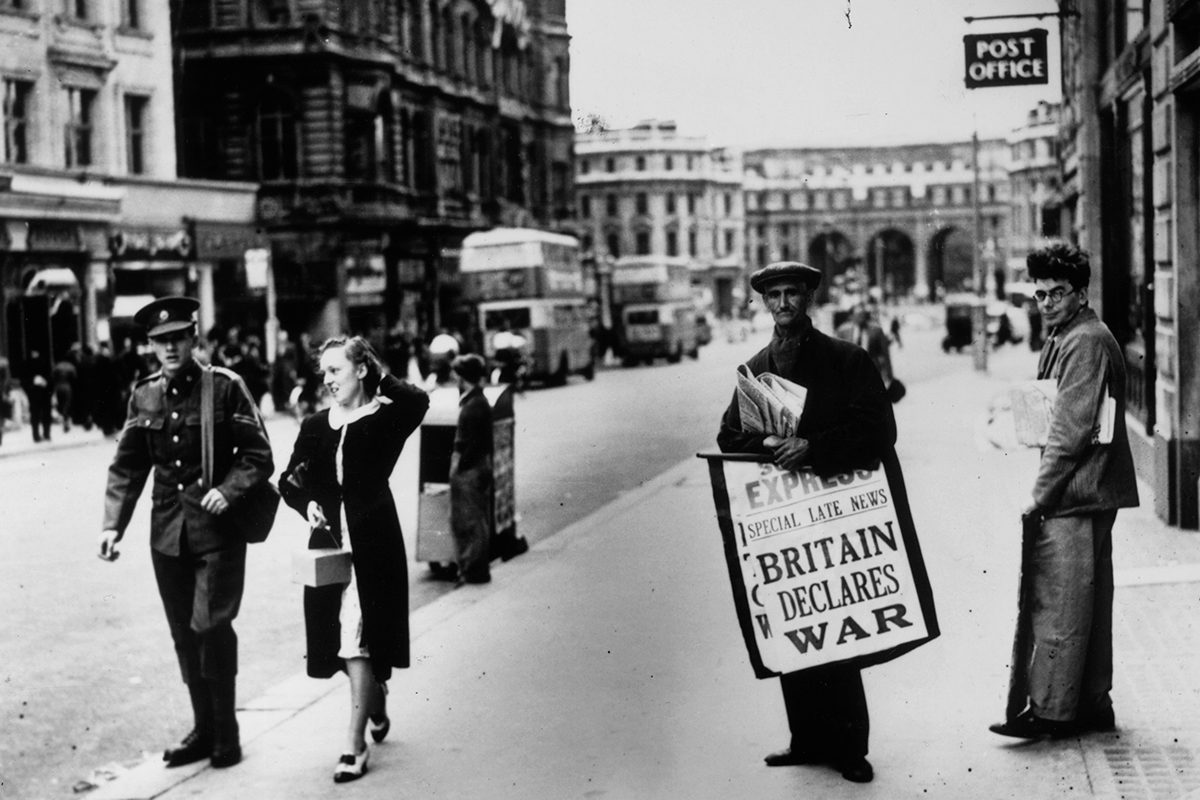 Black and white photograph of a newspaper seller in London holding a hoarding saying 'Britain Declares War'