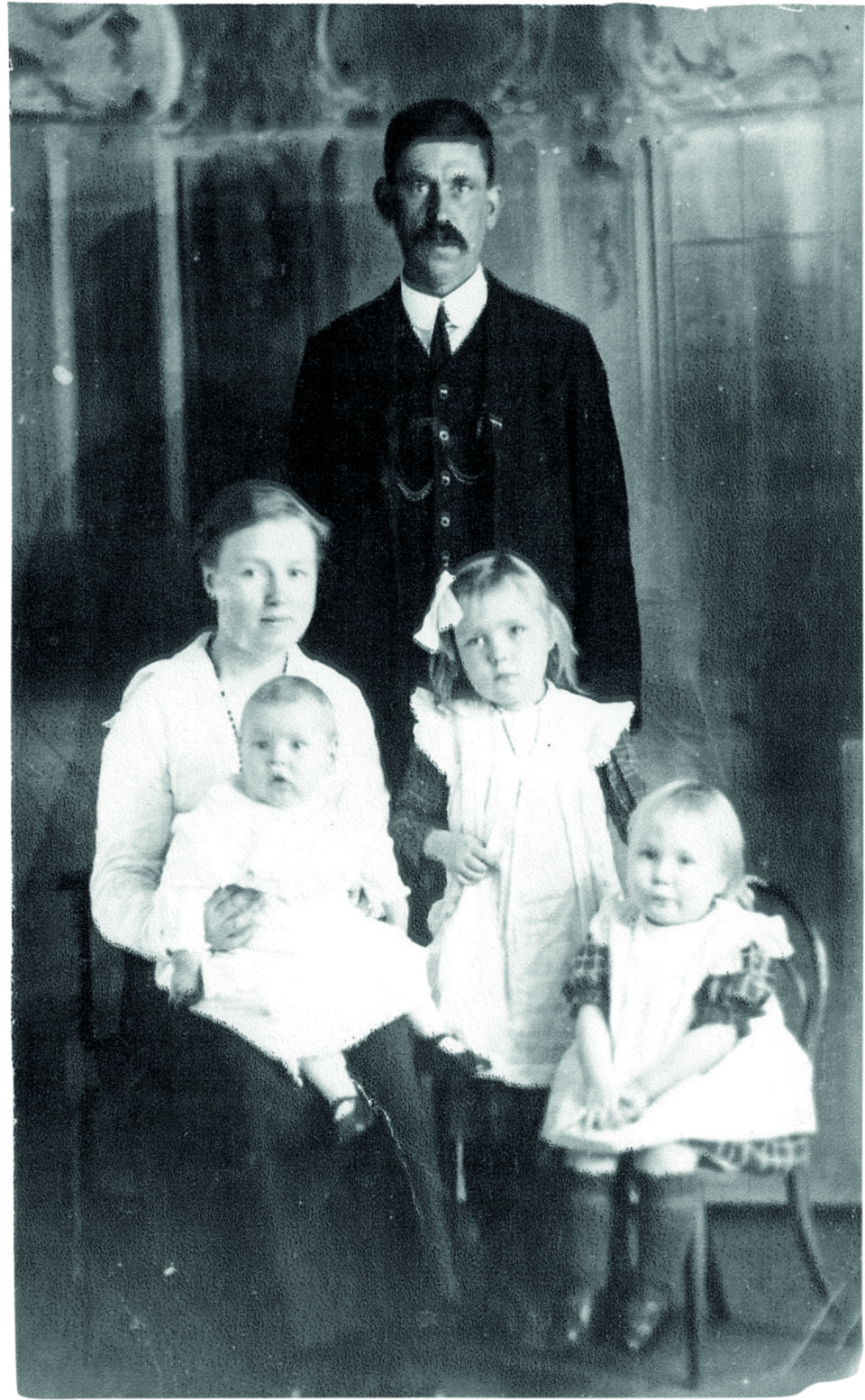 Black and white photograph of a man, a woman and three young children in old-fashioned clothes